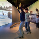 Kinderen in de 'Zaal van de Mens' proberen de mammoet bang te maken door wild met hun armen te zwaaien.